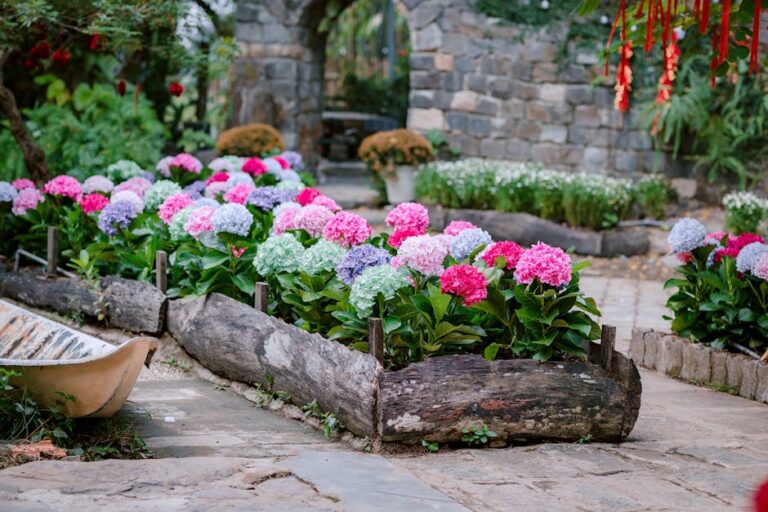 Beeteinfassung mit Feldsteinen – Gartenweg mit Naturstein-Einfassung und blühenden Pflanzen