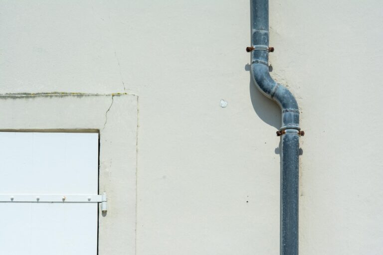Abwasserrohr abdichten – graues Metall-Fallrohr an Hauswand