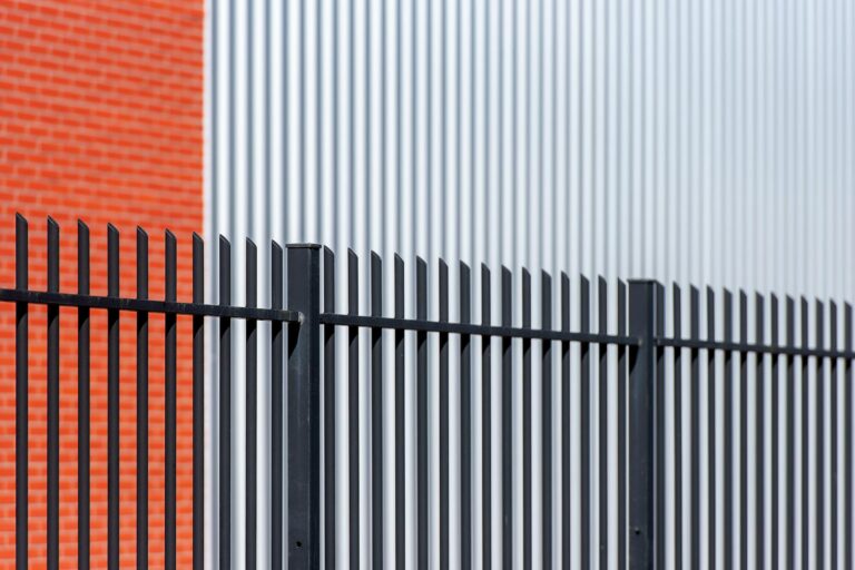 Bauzaun als Gartenzaun – schwarzer Metallzaun an Backsteinmauer