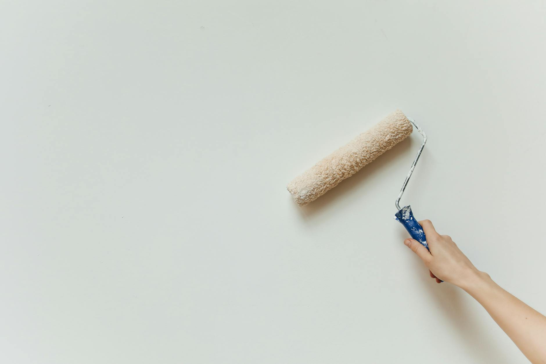 Marmor-Fensterbank streichen – Hand streicht Wand mit Farbroller