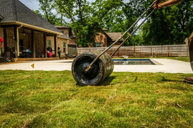 Rasenwalze selber bauen – Person walzt Rasen im sonnigen Hinterhof