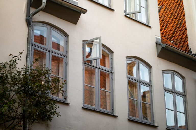 Fliegengitter am Fenster anbringen – weißes Fenster an einer Hausfassade