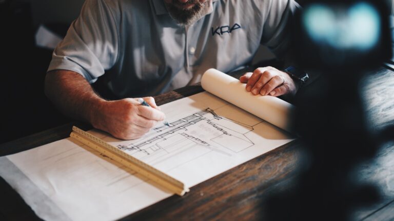 Sicherheitstechnik in der Bauplanung: Kabelwege und Kamerapositionen richtig einplanen An architect working on a draft with a pencil and ruler