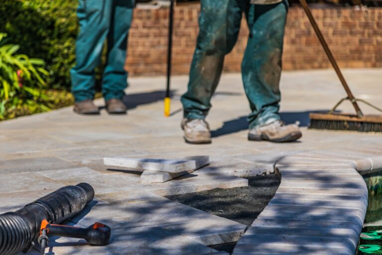 Bodenbeläge für Terrasse und Gartenweg richtig planen Terrassenplatten verlegen: Handwerker beim Verlegen von Platten im Außenbereich