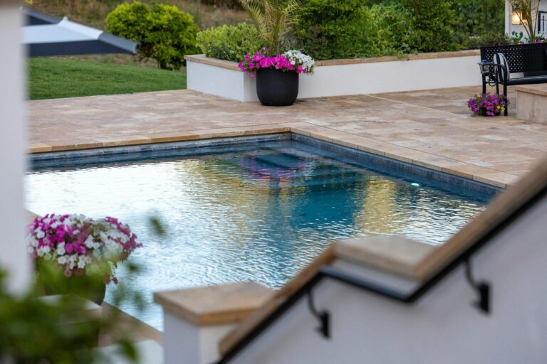 Pool im Neubau mitplanen: Was Bauherren bei Statik, Aushub und Haustechnik beachten sollten Outdoor swimming pool with surrounding patio and vibrant flowers