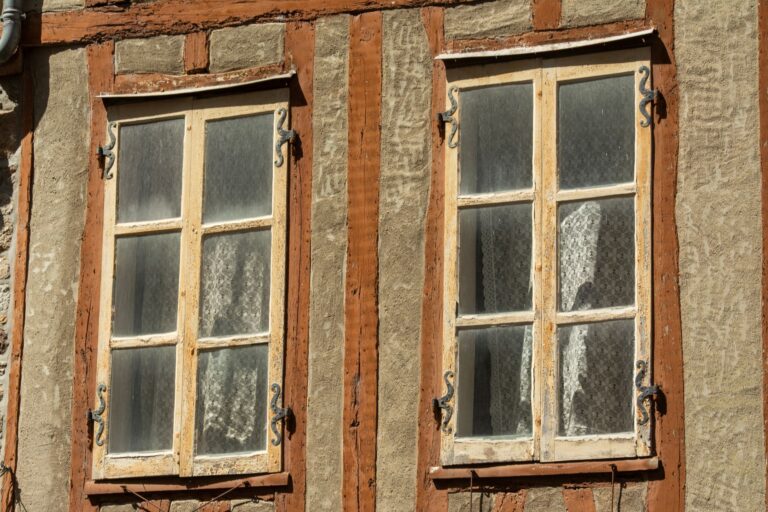 Alte Fenster erkennen – verwitterte Holzfenster an einer Fachwerkfassade