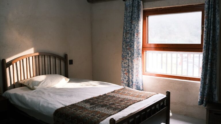Raumklima im Schlafzimmer – Bett vor einem Fenster mit Morgenlicht